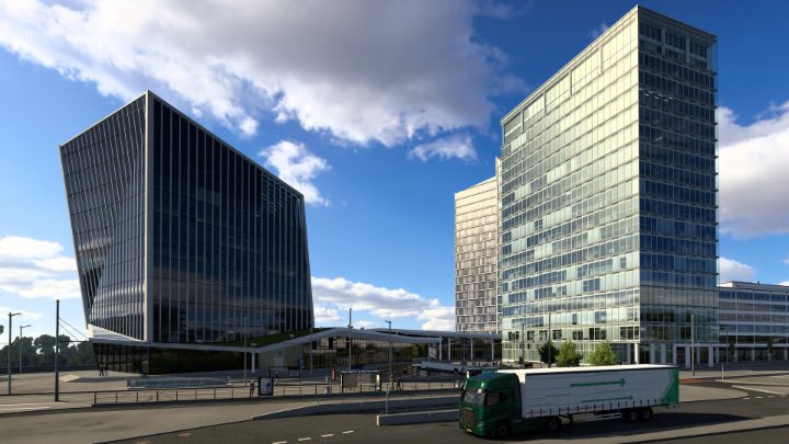 Een groene truck met lange trailer rijdt langs moderne glazen gebouwen op een brede Europese stadsweg.