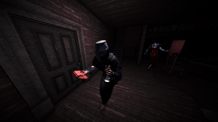 Une silhouette vêtue de noir tient un objet rouge près d’une porte tandis qu’une silhouette pâle en robe rouge s’approche.